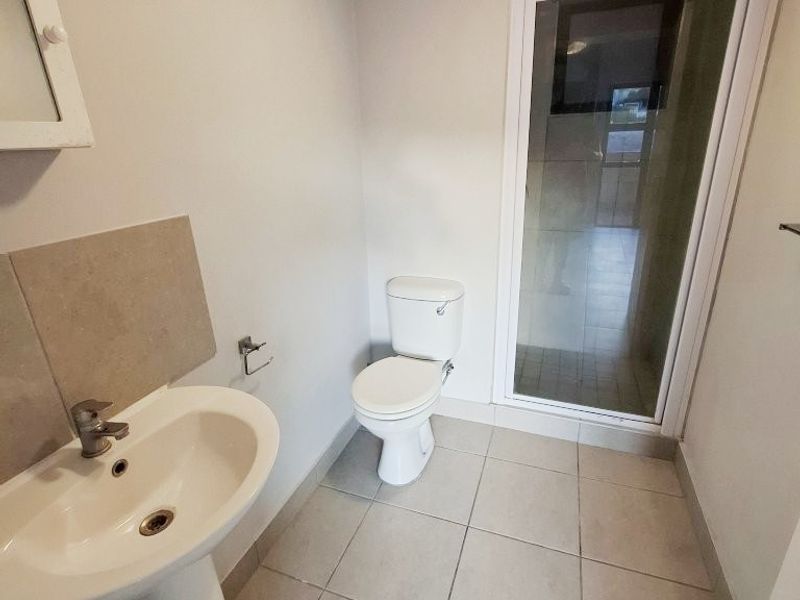 A functional bathroom featuring a pedestal basin, toilet, and a separate shower enclosure with tiled flooring throughout.