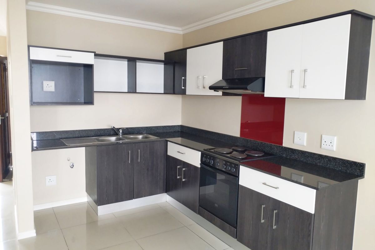 Modern kitchen featuring two-tone cabinetry, granite countertops, a built-in oven with extractor fan, and a stainless steel double sink.