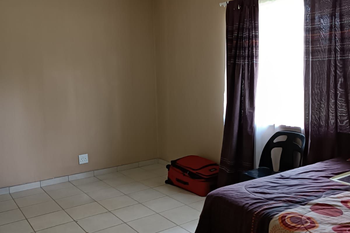 A simple bedroom featuring neutral wall paint and tiled flooring, providing a blank canvas for potential interior design updates.