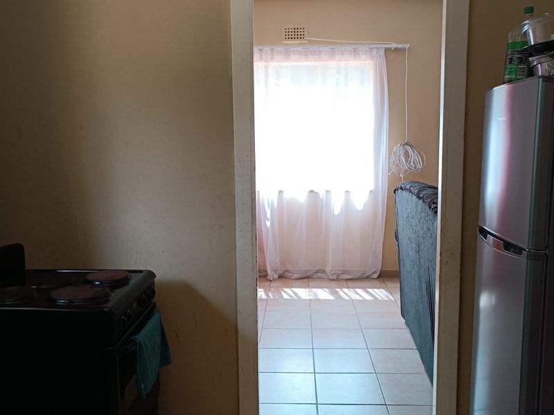 A view from the kitchen looking through a doorway into an adjacent living area, featuring tiled flooring throughout.