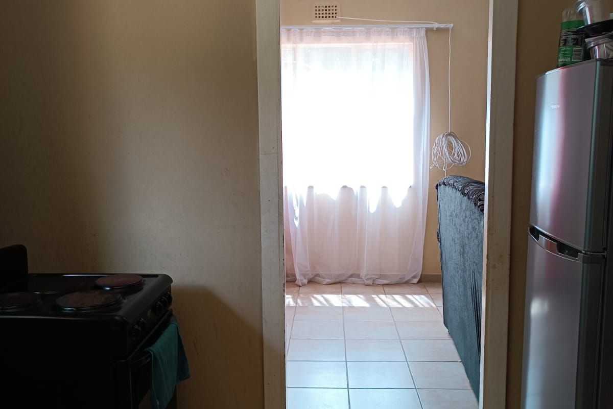 A view from the kitchen looking through a doorway into an adjacent living area, featuring tiled flooring throughout.