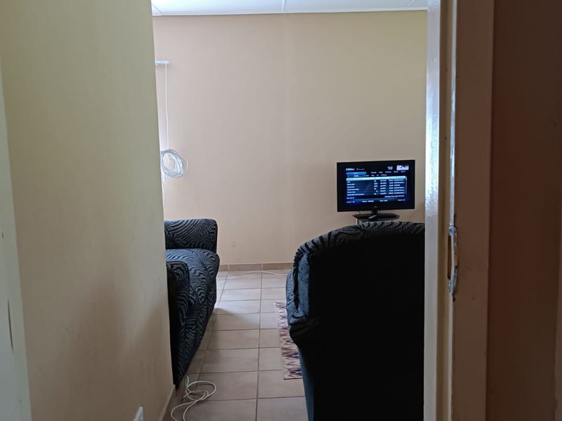 A view into a living room area featuring tiled flooring and neutral wall finishes, currently used as a lounge space.