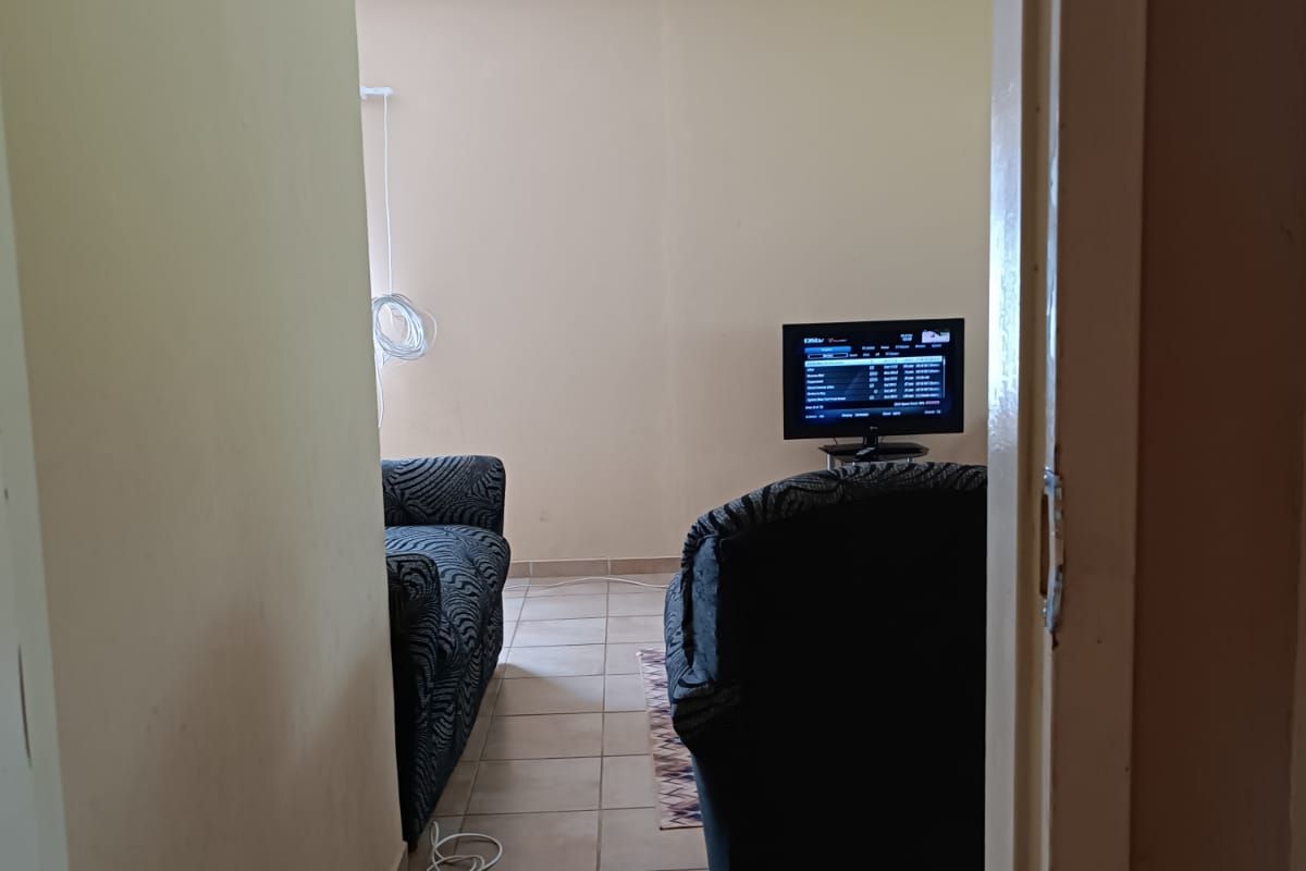 A view into a living room area featuring tiled flooring and neutral wall finishes, currently used as a lounge space.