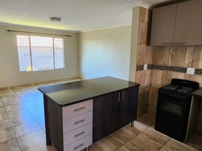 Open plan kitchen and living area featuring tiled flooring, built-in cabinetry, a central kitchen island, and a freestanding stove.