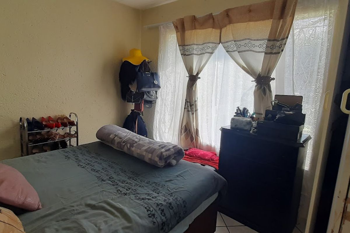 A bedroom featuring a built-in wardrobe and tiled flooring, requiring cosmetic updates to the wall finishes and cabinetry.