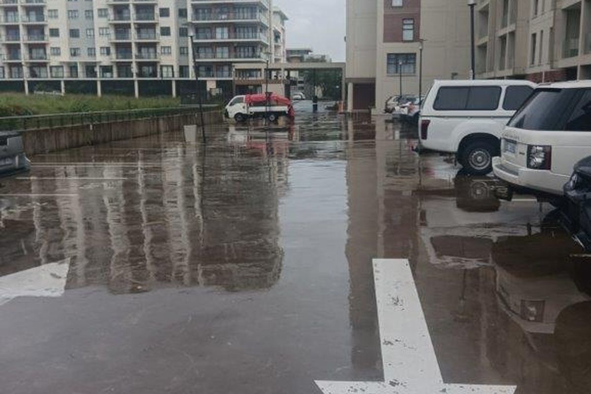 An outdoor parking area between apartment buildings featuring painted directional arrows on the paved surface.