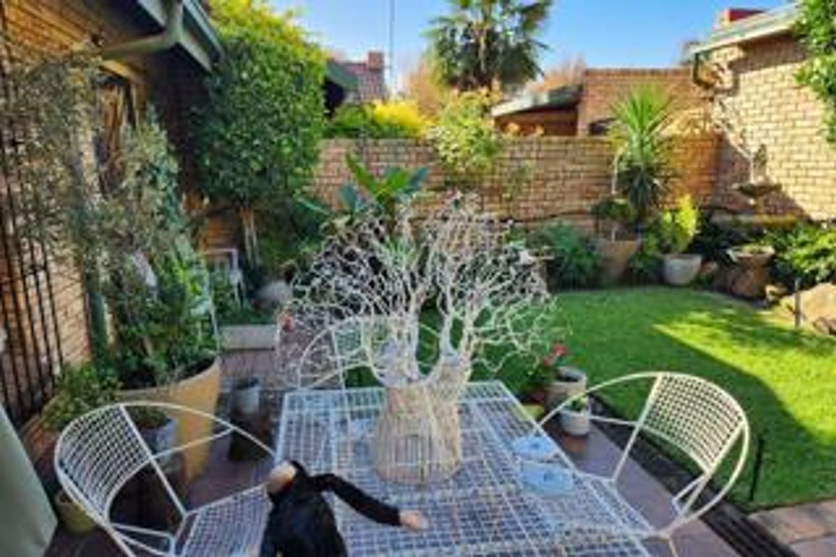 A private rear garden featuring a paved patio area, established lawn, and brick boundary walls, providing a peaceful outdoor space.
