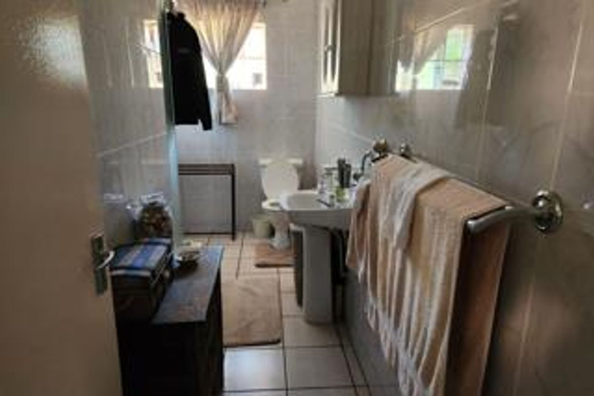 A functional bathroom featuring a pedestal sink, toilet, and tiled walls, offering a practical layout for a townhouse residence.