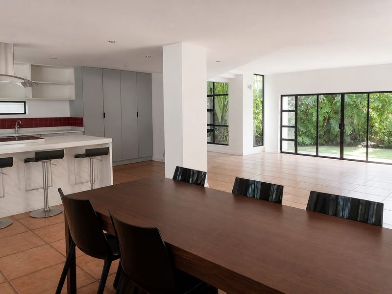 Spacious open-plan living and kitchen area featuring modern cabinetry, a central island, tiled floors, and large sliding doors opening to a lush garden view.