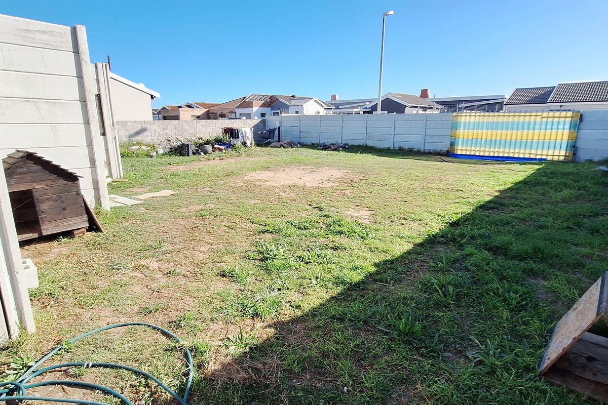 A spacious, fully enclosed backyard featuring concrete panel boundary walls and a grassed area, offering potential for landscaping or outdoor development.