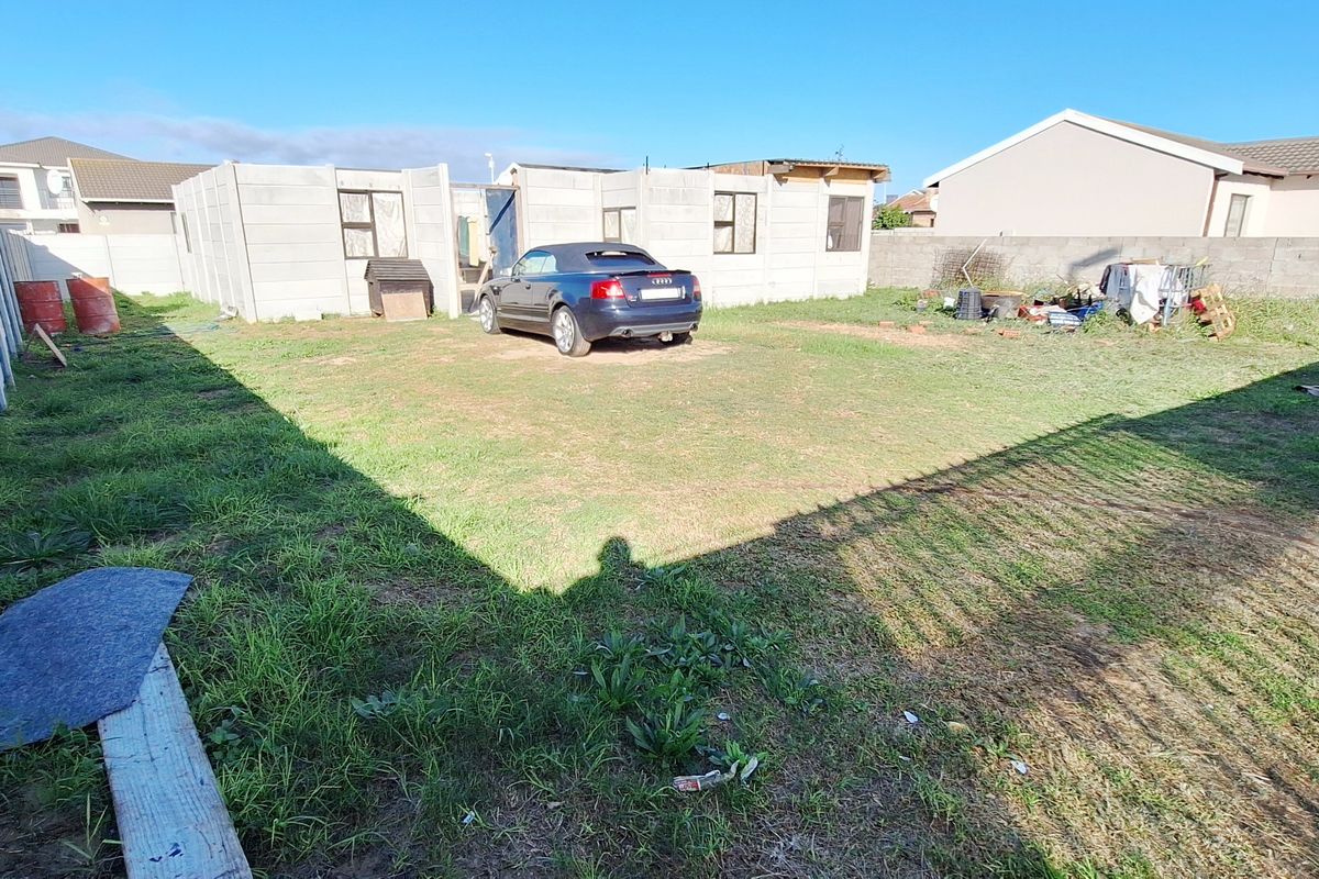 A spacious residential plot featuring a partially constructed concrete structure, enclosed by perimeter boundary walls in a suburban neighborhood setting.