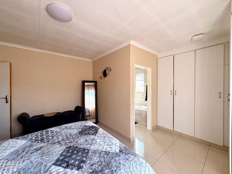A bedroom featuring tiled flooring, built-in wardrobes, and an en-suite bathroom access.