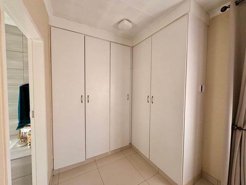 A bedroom featuring built-in floor-to-ceiling white cabinetry with tiled flooring, providing ample storage space.