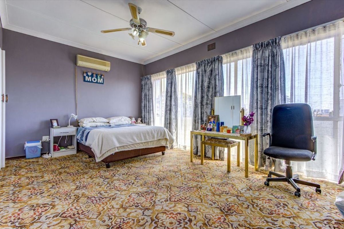 Spacious bedroom featuring a ceiling fan, wall-mounted air conditioning unit, and large windows with floor-to-ceiling curtains.