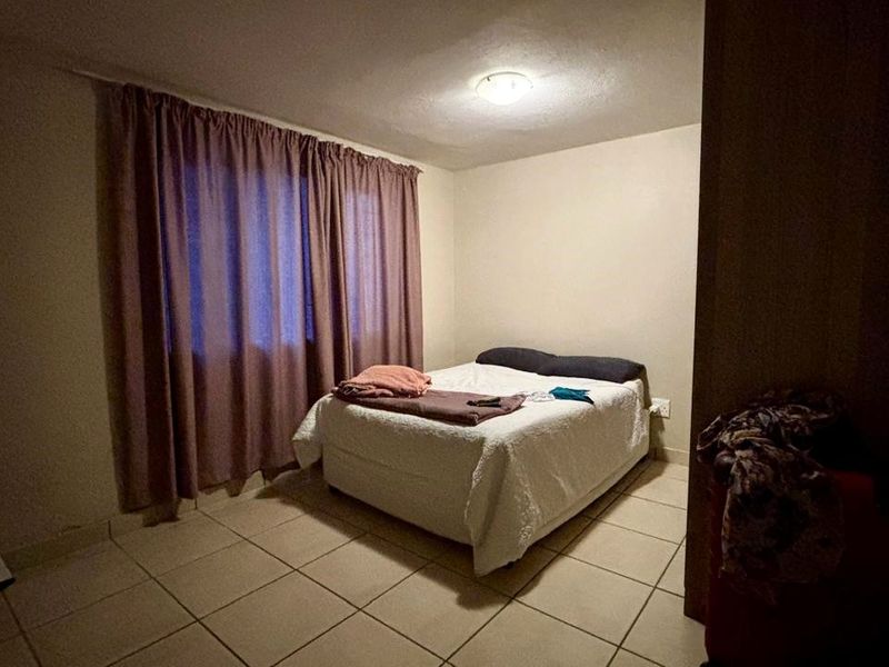 A simple bedroom featuring tiled flooring and a central ceiling light fixture, providing a functional and neutral living space.