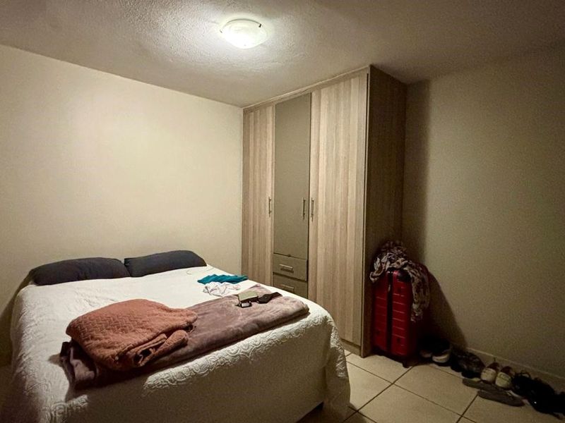 A bedroom featuring a built-in wardrobe and tiled flooring, providing a functional space with neutral wall finishes.