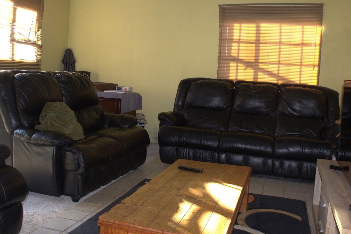 A living room area featuring tiled flooring and window blinds, providing a functional space for relaxation.
