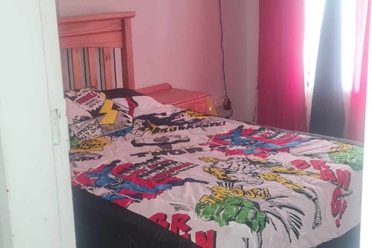 A bedroom featuring laminate flooring and a wall-mounted fan, viewed from the doorway.