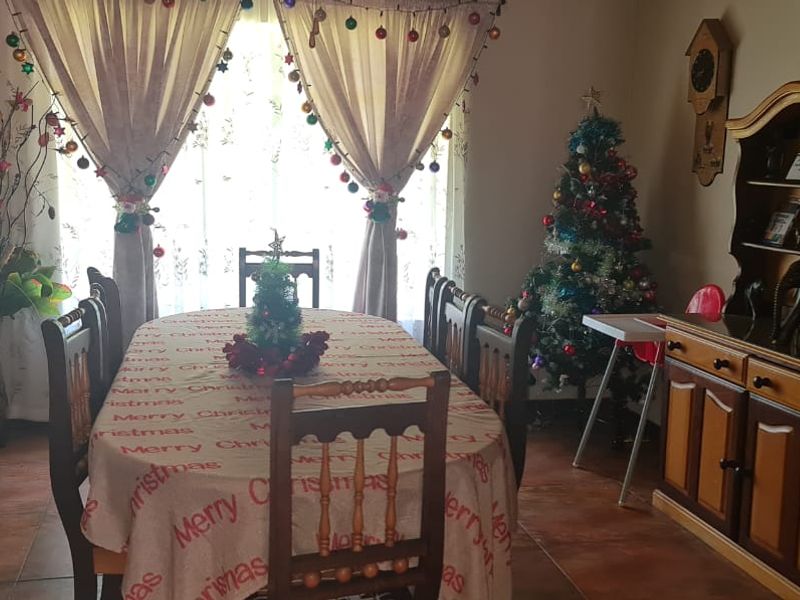 A functional dining room featuring tiled flooring and large windows with curtain rails, providing a comfortable space for family meals.