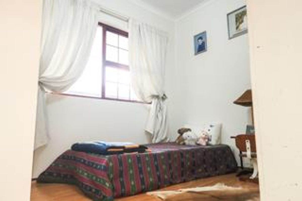A standard bedroom featuring wooden flooring and a window with natural light.
