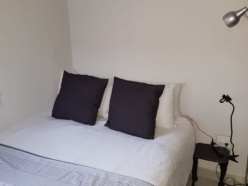 A compact bedroom featuring neutral walls and tiled flooring, providing a functional sleeping space.
