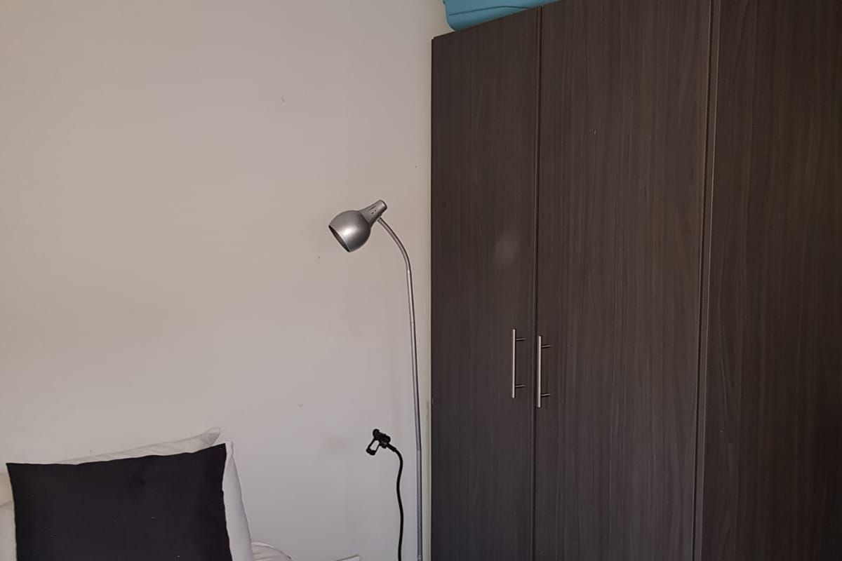 A bedroom featuring a dark wood-finish built-in wardrobe and standard electrical fixtures.