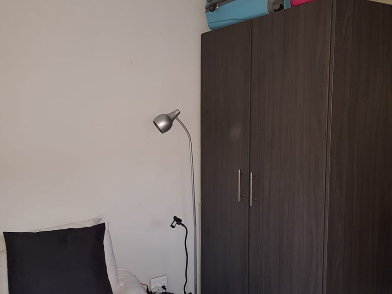 A bedroom featuring a dark wood-finish built-in wardrobe and standard electrical fixtures.