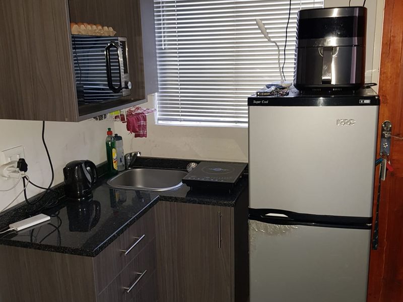 Compact kitchen area featuring dark wood-look cabinetry, granite countertops, and a stainless steel sink, providing essential functionality in a small footprint.