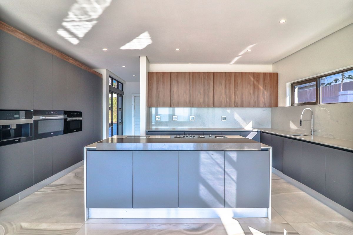 Modern kitchen featuring a central island, high-end built-in appliances, stone countertops, and sleek cabinetry with a contemporary design.