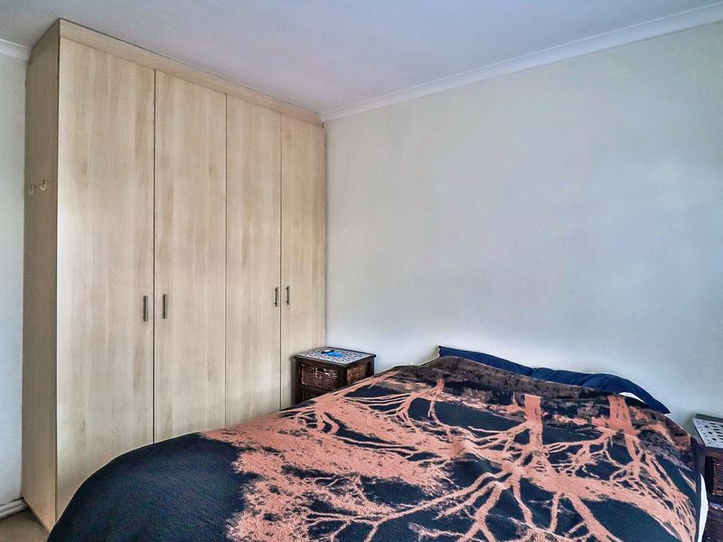 A bedroom featuring light wood-finish built-in wardrobes and coving detail.
