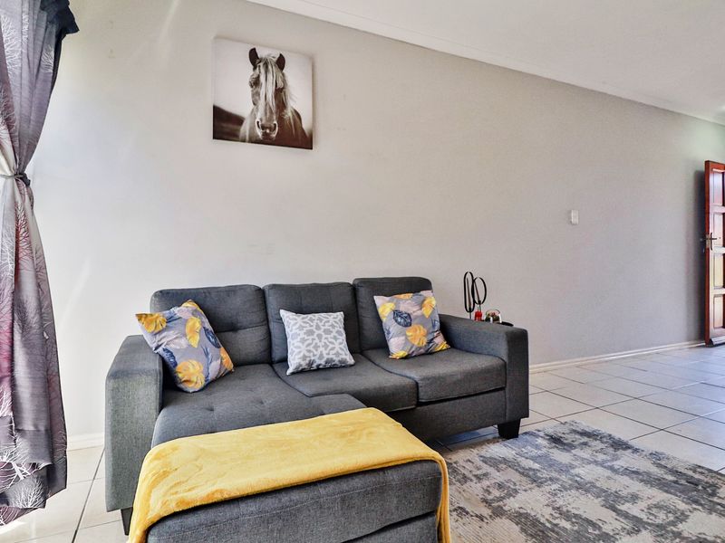 A living room area featuring neutral wall finishes and tiled flooring, with a direct access door leading to the exterior.