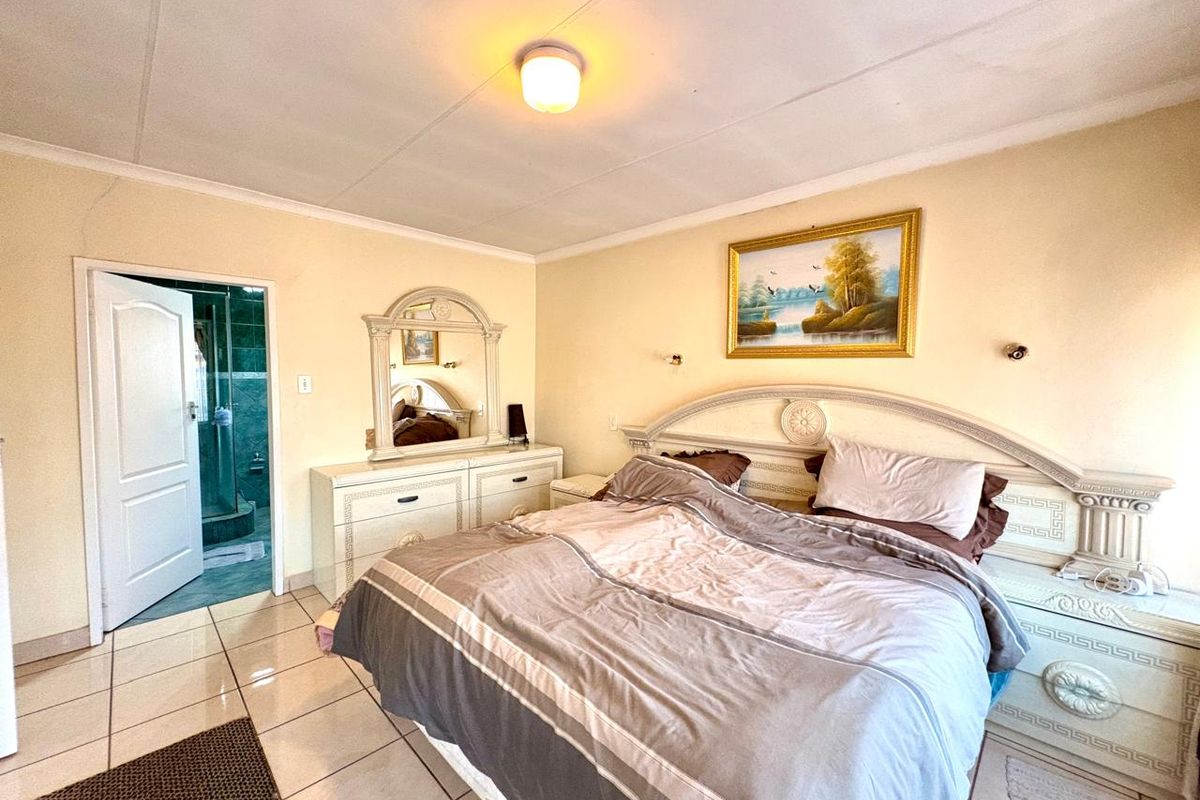 A bedroom featuring tiled flooring, a ceiling light fixture, and an en-suite bathroom access point.