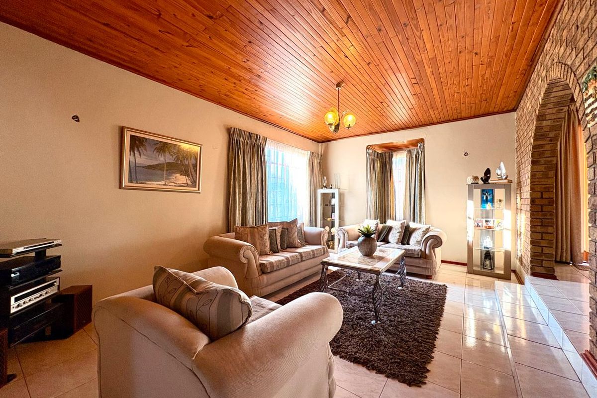 Spacious living room featuring a high timber-clad ceiling, tiled flooring, and a rustic brick archway leading to adjacent areas.
