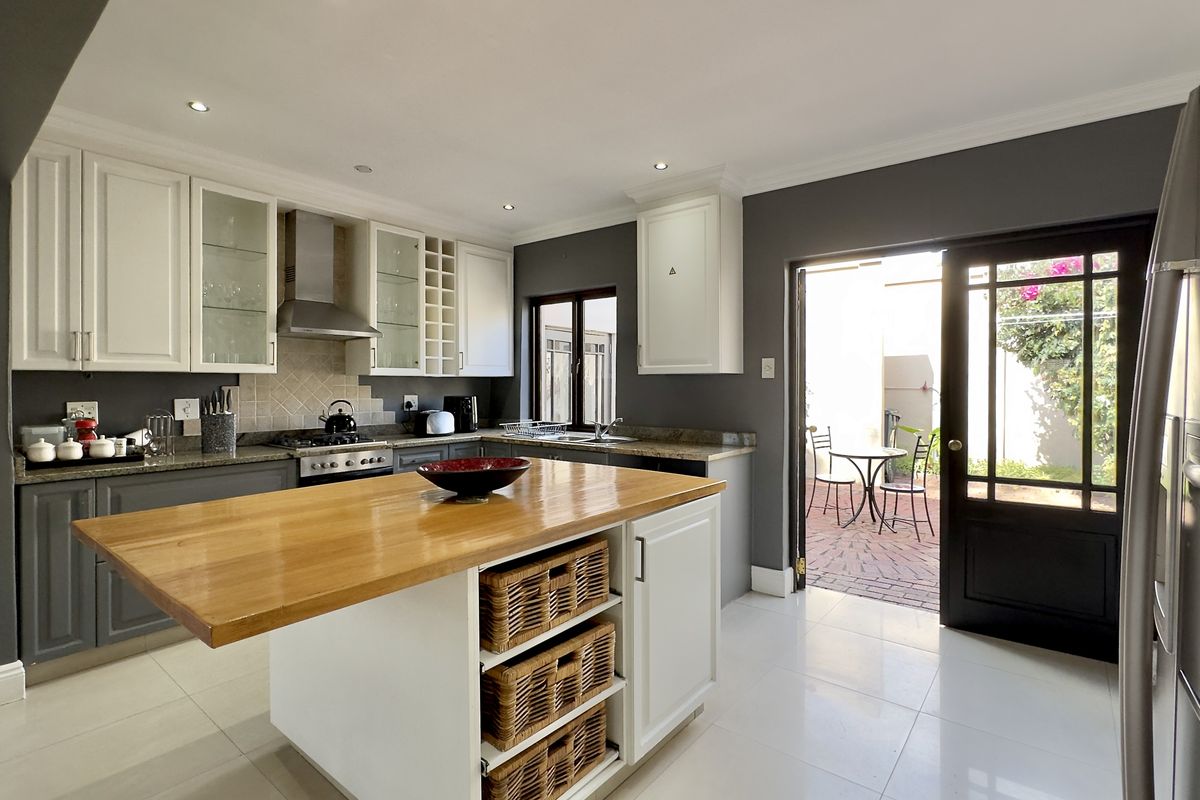Modern kitchen featuring a central island with a wooden countertop, white cabinetry, granite surfaces, and direct access to a paved outdoor patio area.