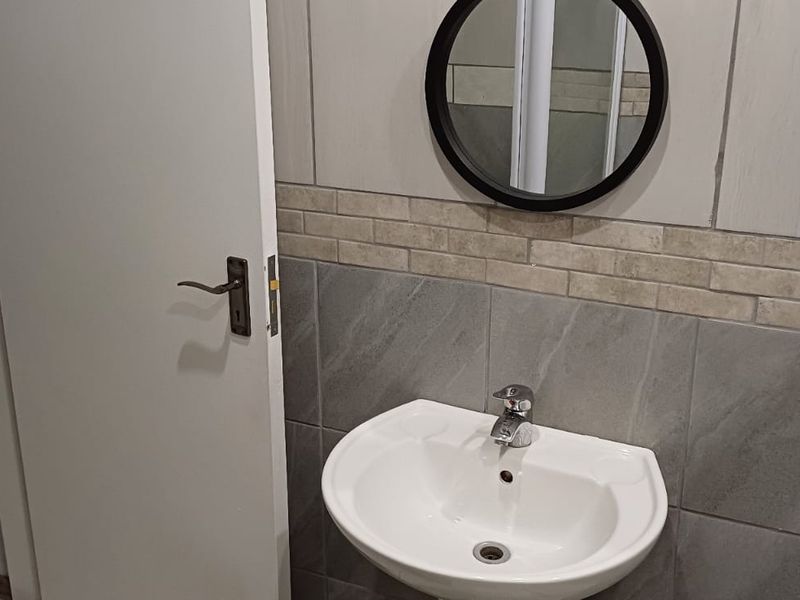 A clean, modern bathroom featuring a wall-mounted basin with a chrome mixer tap and decorative tiled splashback.