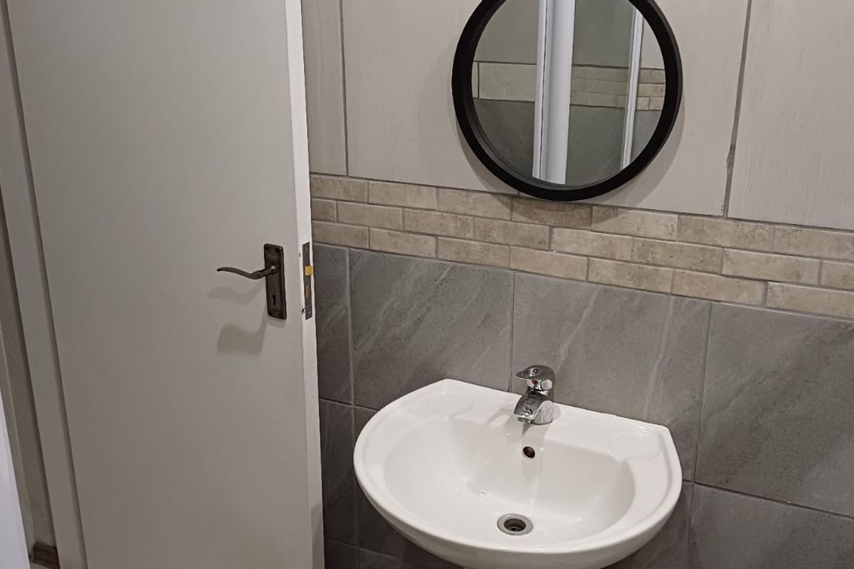 A clean, modern bathroom featuring a wall-mounted basin with a chrome mixer tap and decorative tiled splashback.