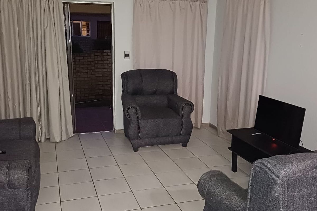 A living room featuring tiled flooring and a sliding glass door providing access to an outdoor area.