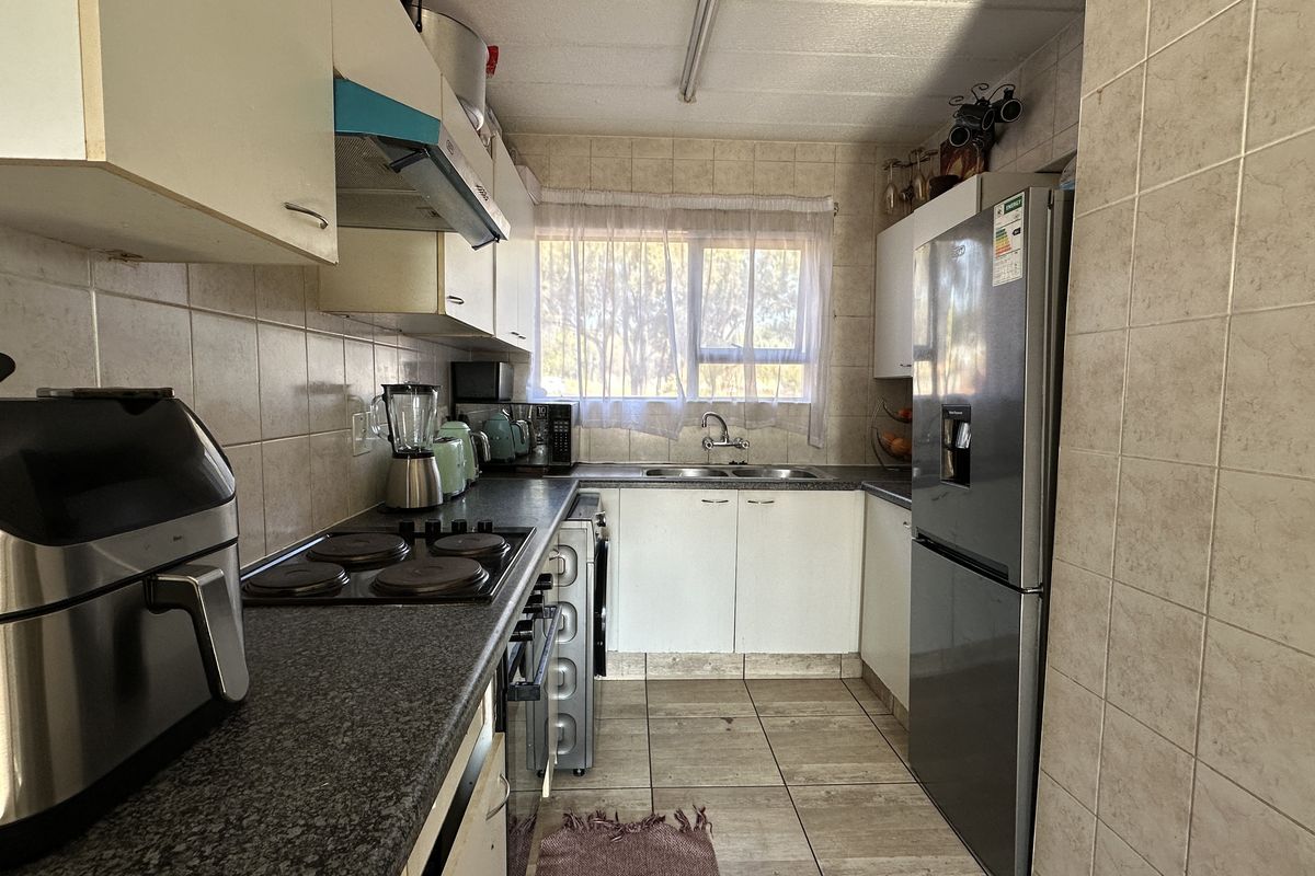 A functional galley-style kitchen featuring tiled walls, laminate countertops, built-in cabinetry, and a double basin sink.