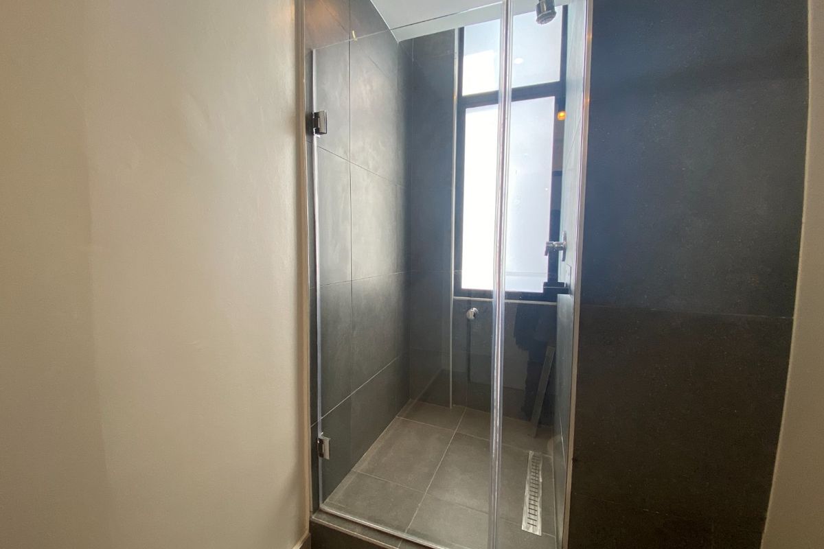 Modern walk-in shower featuring dark grey wall tiles, a glass enclosure, and a linear floor drain, providing a sleek and contemporary bathroom aesthetic.
