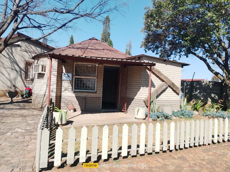 Exterior view of a small holding cottage featuring a circular design, brick facade, metal security gate, and a small front garden area.