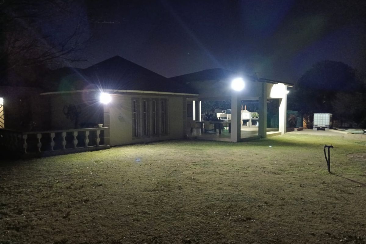 Night view of the rear exterior of the property, featuring a covered patio area and a spacious garden.