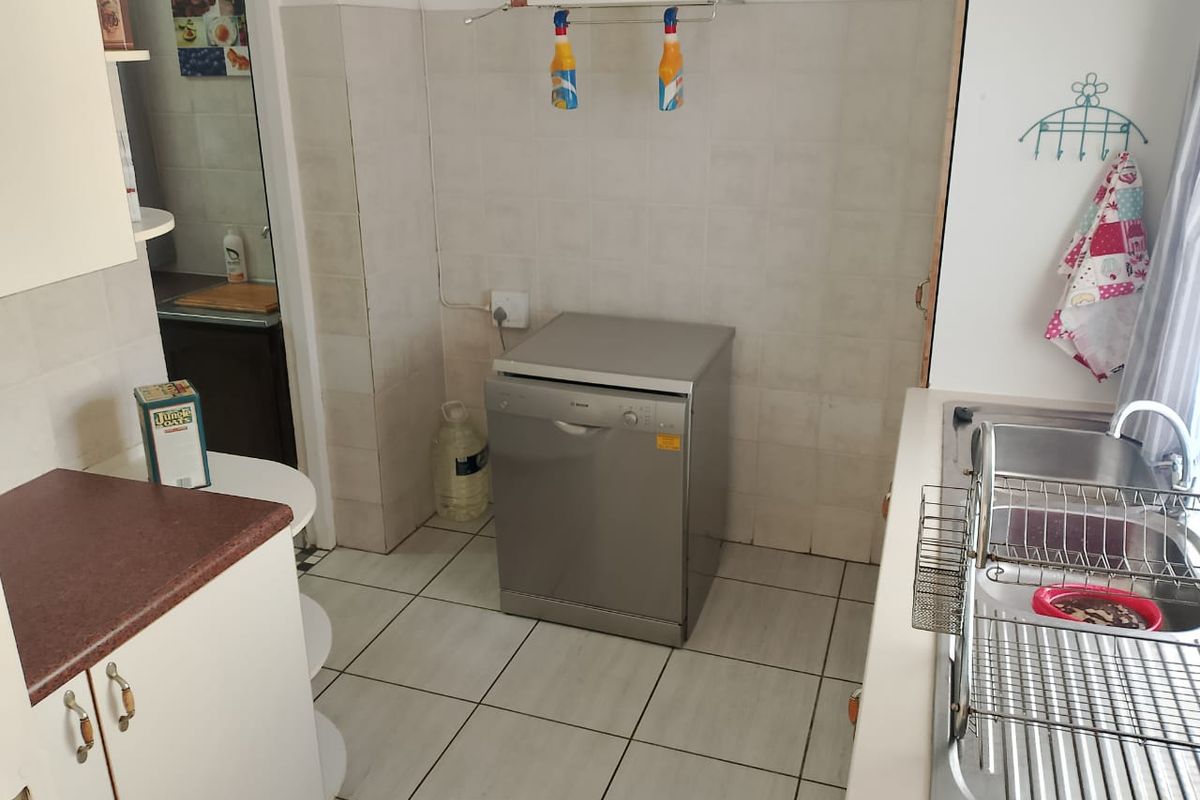 Functional kitchen area featuring tiled flooring, built-in cabinetry, a stainless steel sink, and dedicated space for a dishwasher.