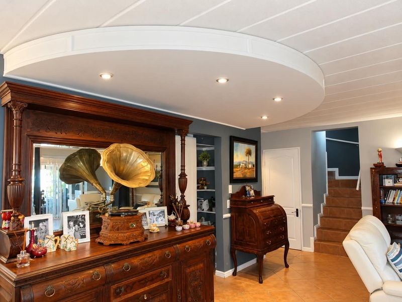A well-maintained living area featuring a distinctive curved bulkhead ceiling with recessed lighting, tiled floors, and a staircase leading to the upper level.
