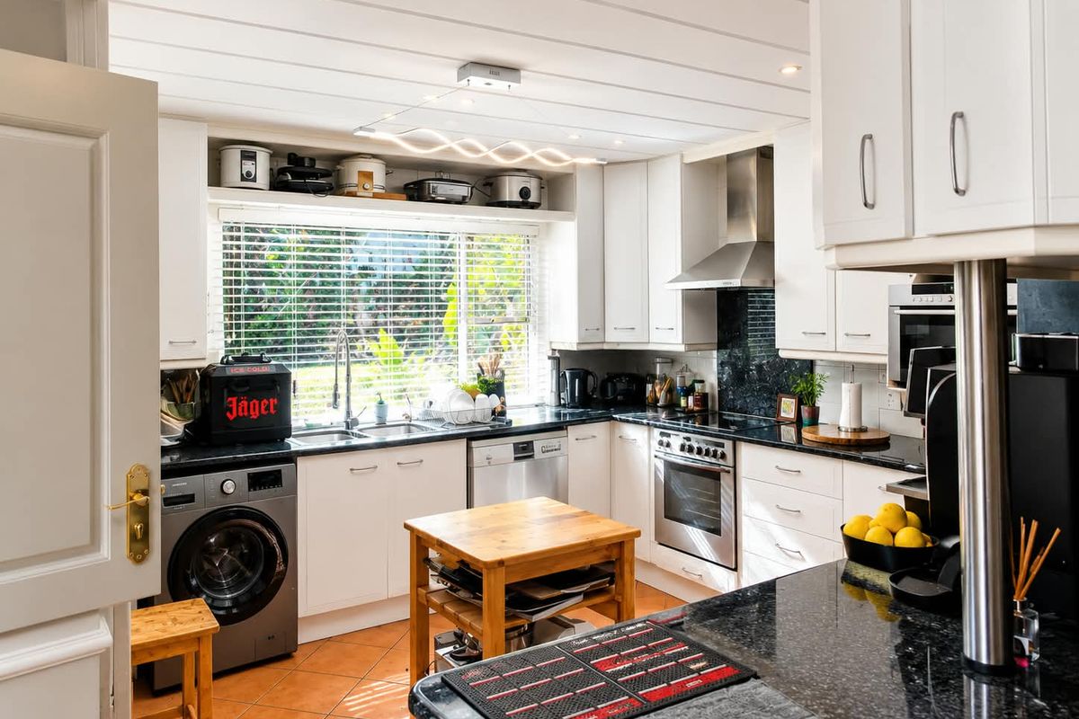 A functional kitchen featuring white cabinetry, granite countertops, stainless steel appliances, and tiled flooring, with ample natural light from the window.