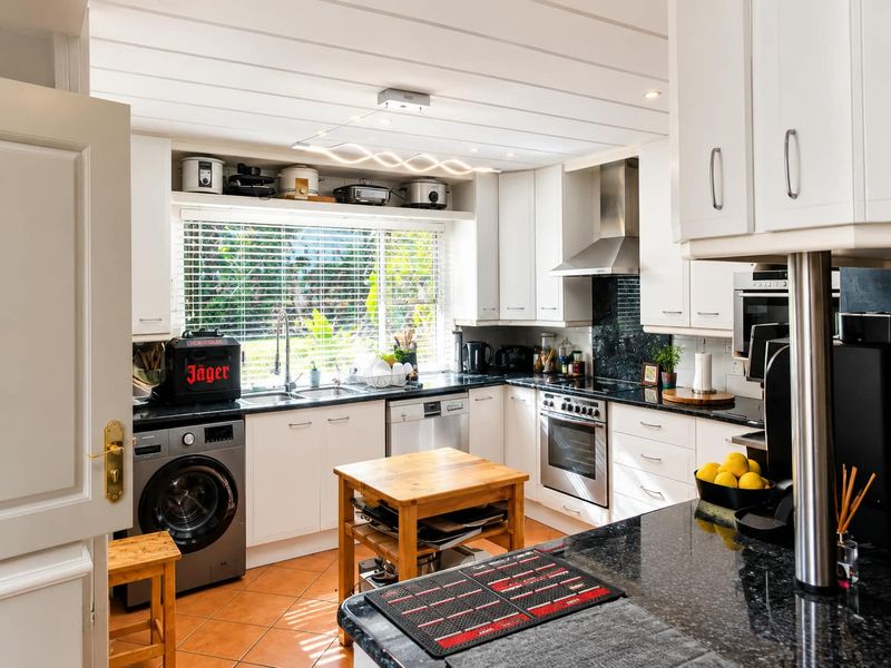 A functional kitchen featuring white cabinetry, granite countertops, stainless steel appliances, and tiled flooring, with ample natural light from the window.
