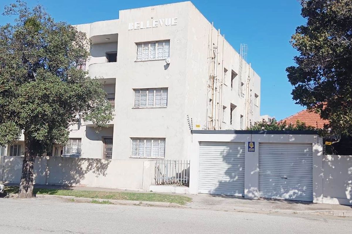 Street view of the Bellevue apartment building featuring a multi-story facade, secure roller shutter garage doors, and perimeter electric fencing.