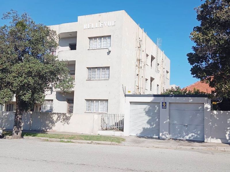 Street view of the Bellevue apartment building featuring a multi-story facade, secure roller shutter garage doors, and perimeter electric fencing.
