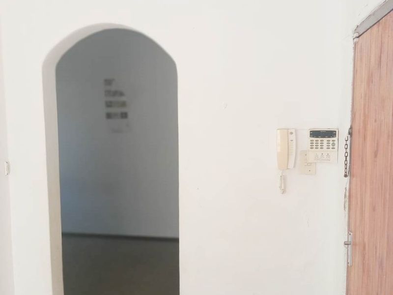 An entry area featuring an arched doorway, an integrated intercom system, and a security chain on the front door.