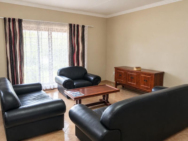 A spacious living room featuring neutral wall tones, tiled flooring, and a large sliding glass door providing natural light.