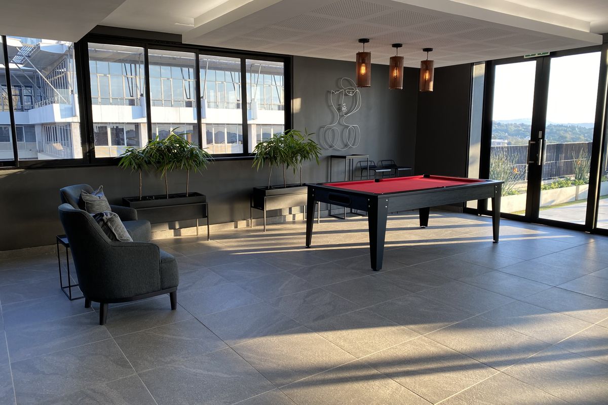 Modern, spacious living area featuring large format floor tiles, recessed ceiling detail, and expansive glass doors leading to an outdoor space.